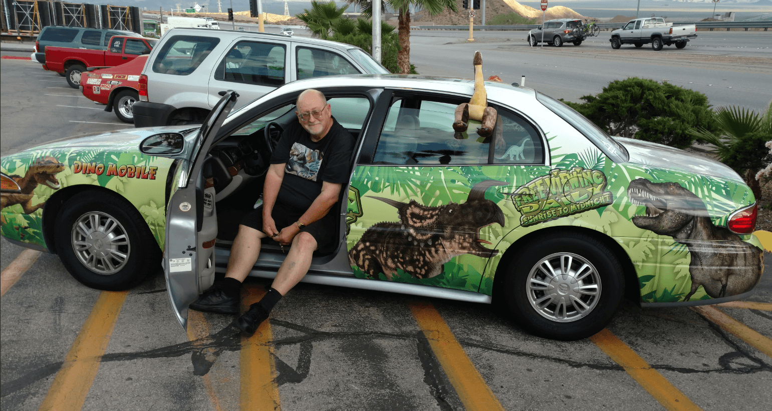 the dinosaur man sitting in his fully wrapped decorated car covered with jungle and dinosaurs